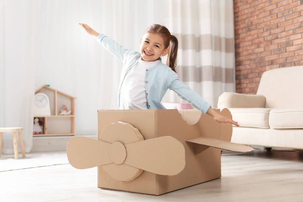 Cute little boy playing with binoculars and cardboard airplane in bedroom - Foto, Imagen
