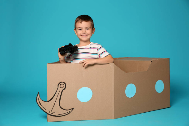 Cute little boy playing with binoculars and cardboard airplane in bedroom - Foto, imagen