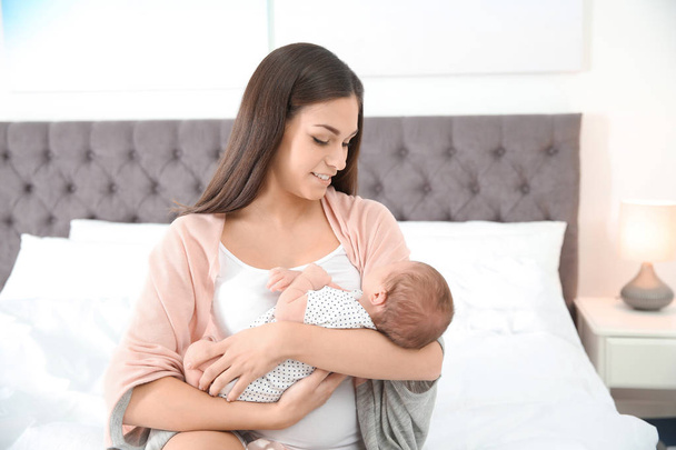 Young woman with her newborn baby in bedroom - Photo, image