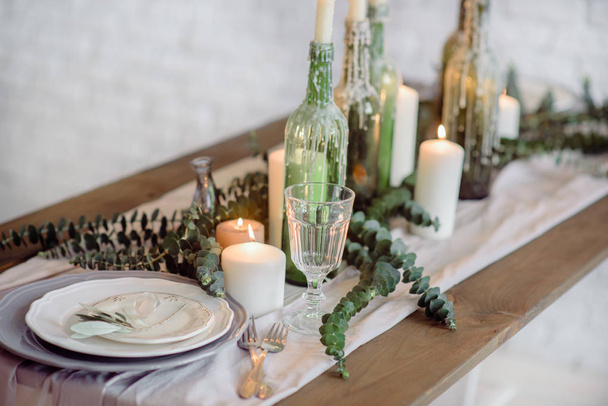 Wedding. Banquet. The chairs and table for guests, decorated with candles, served with cutlery and crockery and covered with a tablecloth. The table stands on a green lawn - Foto, Bild