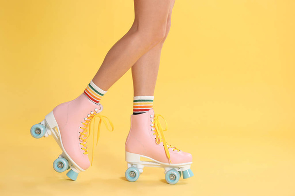 Young woman with retro roller skates on color background, closeup - Foto, afbeelding