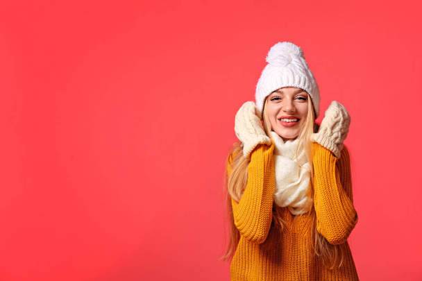 Portrait of emotional young woman in stylish hat, sweater and mittens on color background, space for text. Winter atmosphere - Foto, Bild