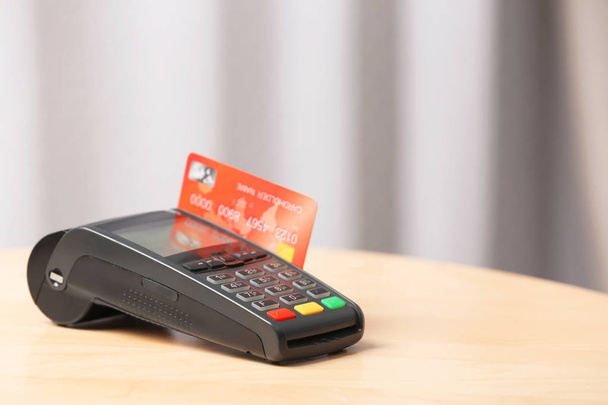Modern payment terminal with credit card on table indoors. Space for text - Fotografie, Obrázek