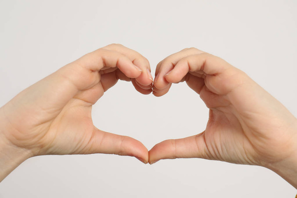 Young woman making heart with her hands on light background - Photo, image