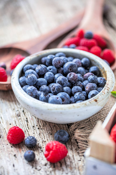 close-up view of delicious healthy blueberries in bowl on wooden table - Фото, изображение