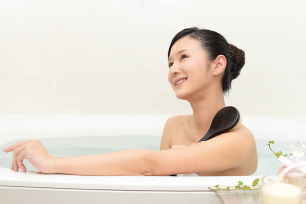 Beautiful young woman taking a relaxing bath - Фото, изображение