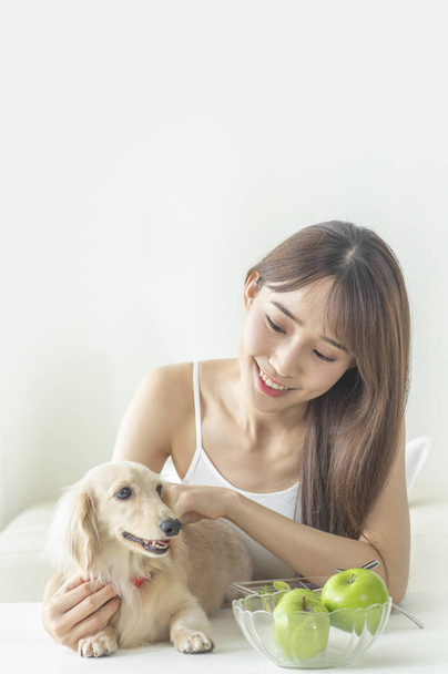 Portrait of Young woman with dog at home - 写真・画像