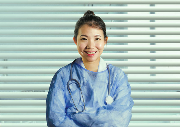 young happy and attractive Asian Korean medicine doctor woman in blue scrubs smiling cheerful posing corporate at hospital office window in health care and successful medical career concept - Fotoğraf, Görsel