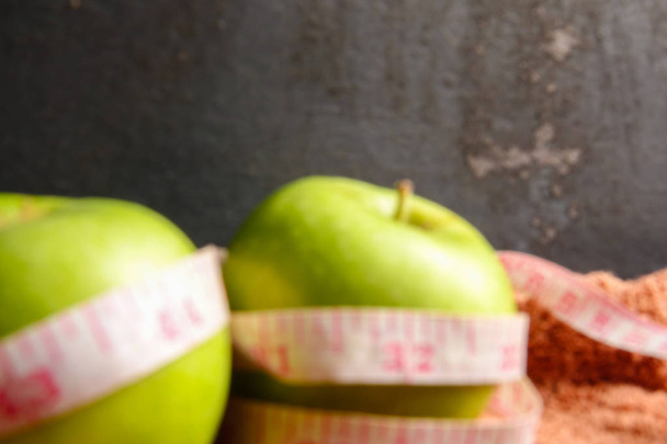 Health-Lifestyle-Konzept: grüne Äpfel und Maßband vor schwarzem rustikalem Hintergrund. Selektiver Fokus. - Foto, Bild