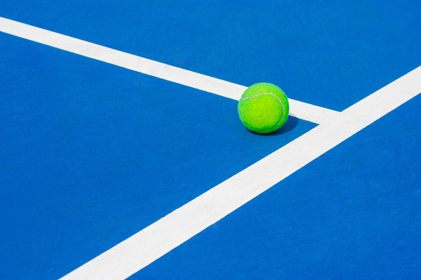 Πράσινη μπάλα που πέφτουν στο πάτωμα σχεδόν λευκό γραμμές υπαίθριο μπλε σκληρό γήπεδο τένις σε δημόσιο πάρκο. (Επιλεκτική εστίαση) - Φωτογραφία, εικόνα