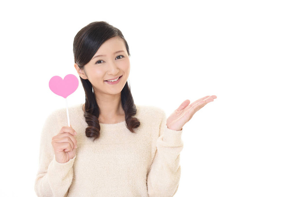 Hymyilevä nainen pitelee vaaleanpunainen sydän rakkaus symboli
 - Valokuva, kuva