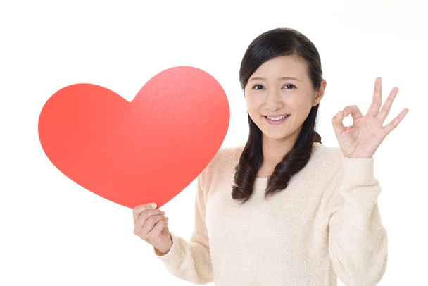 Mujer sonriente sosteniendo el símbolo de amor corazón rojo
 - Foto, imagen