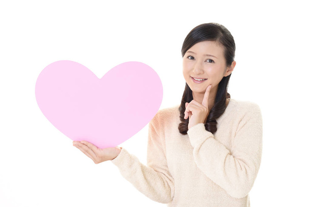 Hymyilevä nainen pitelee vaaleanpunainen sydän rakkaus symboli
 - Valokuva, kuva