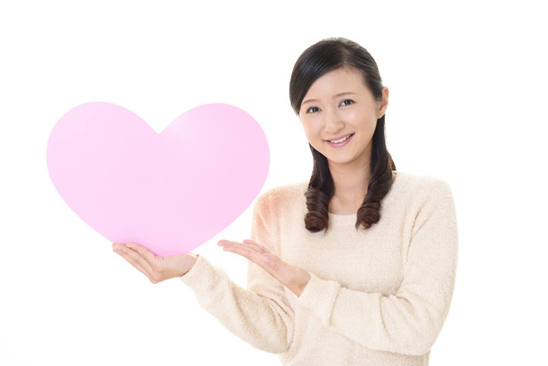 Smiling woman holding pink heart love symbol - Photo, Image