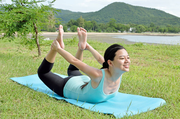 Jovem fazendo ioga de manhã perto do lago
  - Foto, Imagem
