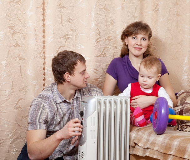 Family at home near oil heater - Foto, Imagem