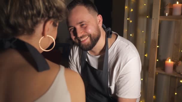 Paar schaut einander an und Mädchen berührt Mann mit schmutzigem Finger in Tonwerkstatt - Filmmaterial, Video