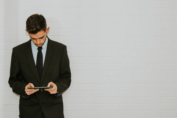 business man in white wall consulting the device or tablet - Foto, Imagem