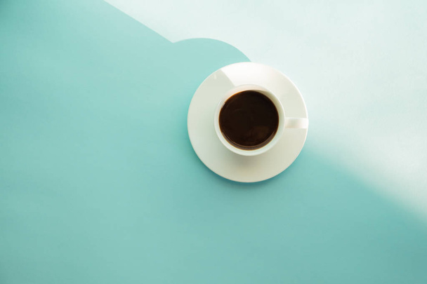 Чашка парящего кофе на зеленом столе с морской пеной, вид сверху. Абстрактное фото горячего эспрессо на бледно-сине-зеленом фоне
. - Фото, изображение