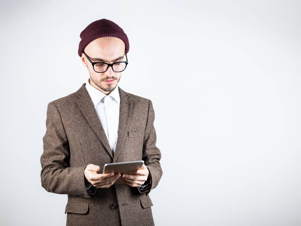 Serious man in tweed jacket with a tablet computer. Male person in hipster style clothing uses technology, studio shot in white background - Foto, immagini