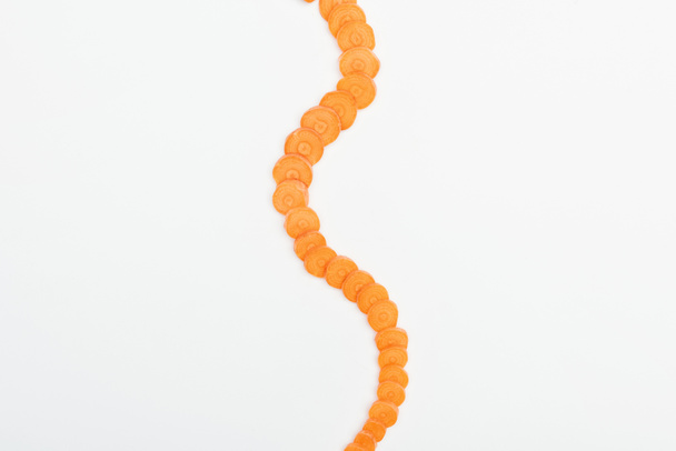 Draufsicht auf reife rohe Karottenscheiben in vertikaler, gekrümmter Linie isoliert auf weiß angeordnet - Foto, Bild