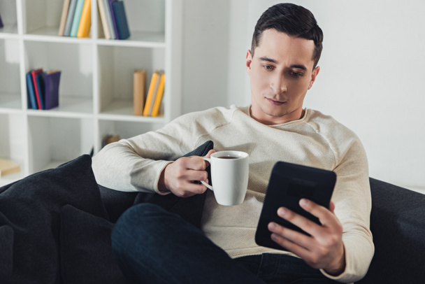 gerichte mens studie met e-boek zittend op de Bank thuis  - Foto, afbeelding