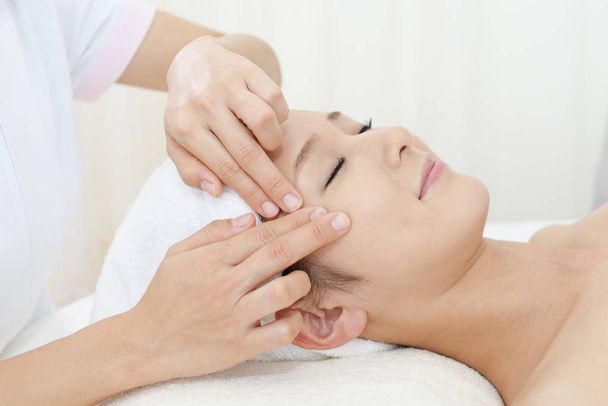 Beautiful young woman receiving facial massage - Fotoğraf, Görsel