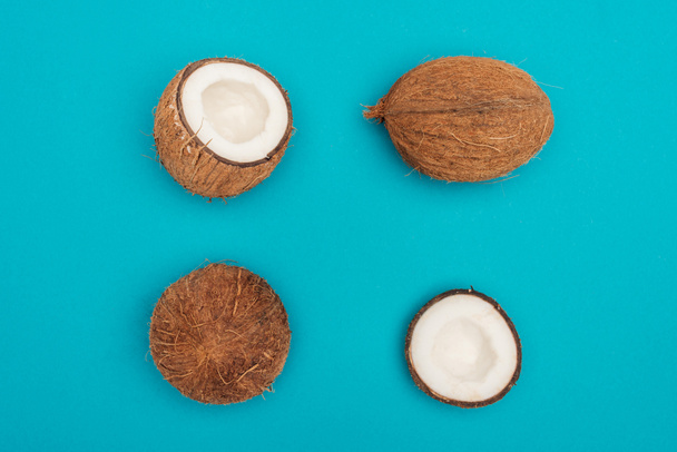 top view of whole coconuts and coconut halves on blue background - Foto, immagini