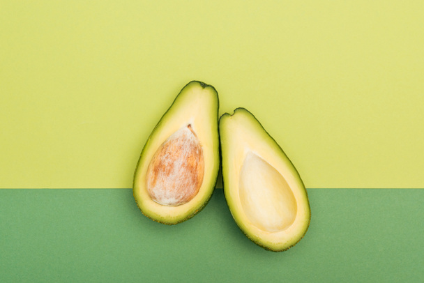 top view of fresh ripe avocado halves on bicolor background - Фото, изображение