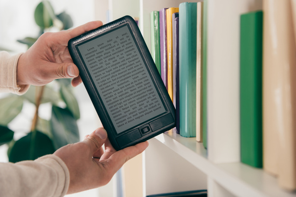 cropped view of man taking ebook from bookshelf - 写真・画像