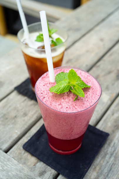  a pink strawberry smoothie with mint leaf on the wooden table - Foto, Imagen