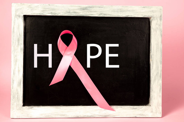 the text world cancer day and a pink ribbon on a table background - Foto, Imagen
