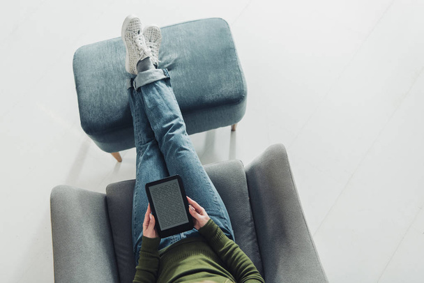 Draufsicht der Frau, die mit eBook studelt und zu Hause im Sessel sitzt - Foto, Bild