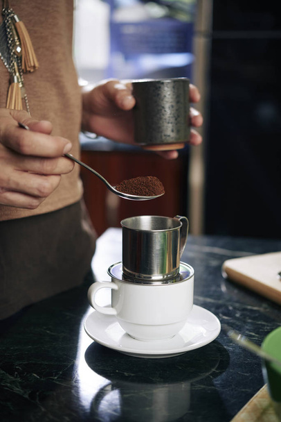 Manos de persona poniendo café en el filtro vietnamita
 - Foto, imagen
