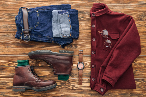Flat lay with leather boots, jeans and shirt on wooden background - Foto, Bild