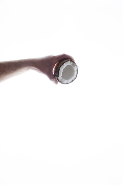 Κατακόρυφη βολή της αρσενική χέρι εκμετάλλευση καρύδας και χύνοντας γάλα καρύδας από το - Φωτογραφία, εικόνα