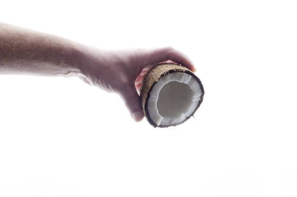 Conceito de derramamento de leite de coco de coco fresco saboroso na mão masculina contra o fundo chicote
 - Foto, Imagem