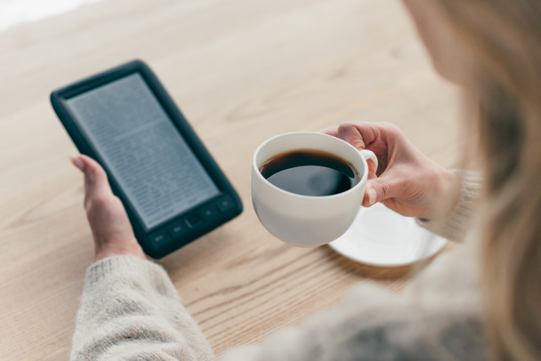 bijgesneden beeld van vrouw studie met e-boek en houden cup met koffie - Foto, afbeelding