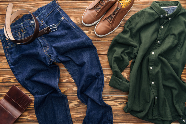 Вид сверху зеленой рубашки, обуви и джинсов на деревянном фоне
 - Фото, изображение