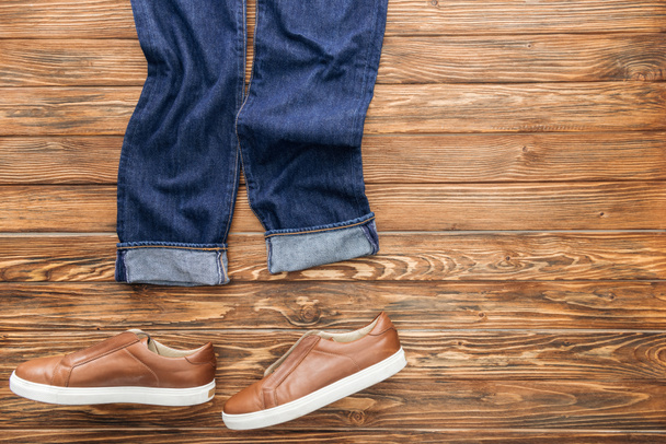 Top view of jeans and brown shoes on wooden background - Photo, Image