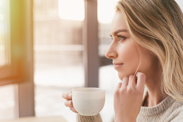 dreamy woman looking at window and holding cup - Photo, Image