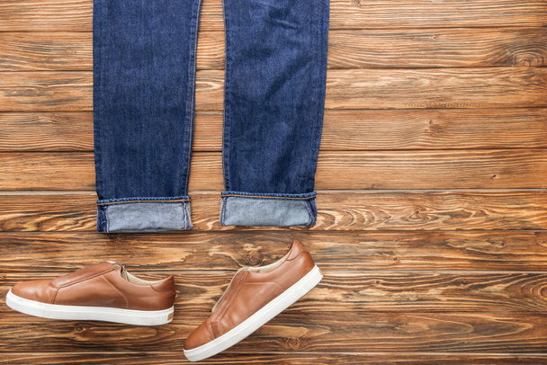Вид сверху синих джинсов и ботинок на деревянном фоне
 - Фото, изображение