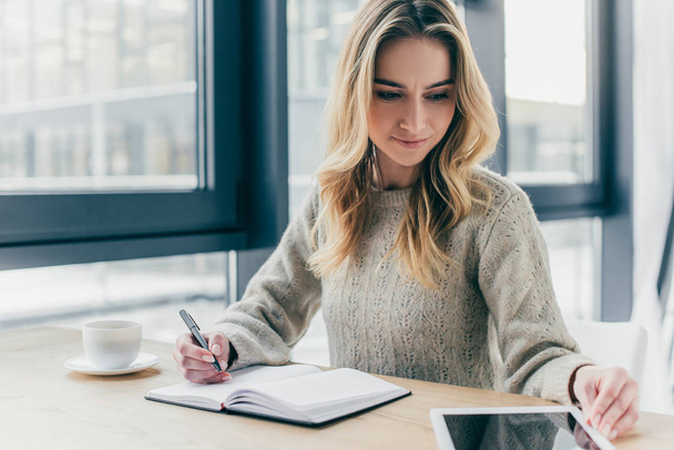 beautiful woman studing with digital tablet while holding pen near notebook - Φωτογραφία, εικόνα