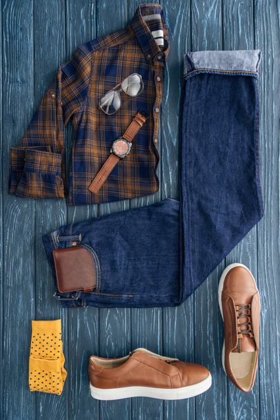 Flat lay com camisa quadriculada na moda, jeans e botas marrons em fundo de madeira
 - Foto, Imagem