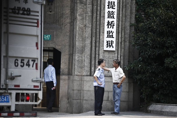 A Chinese man talks with a police officer outside Tilanqiao Prison in downtown Shanghai, China, 11 July 2013 - Фото, зображення