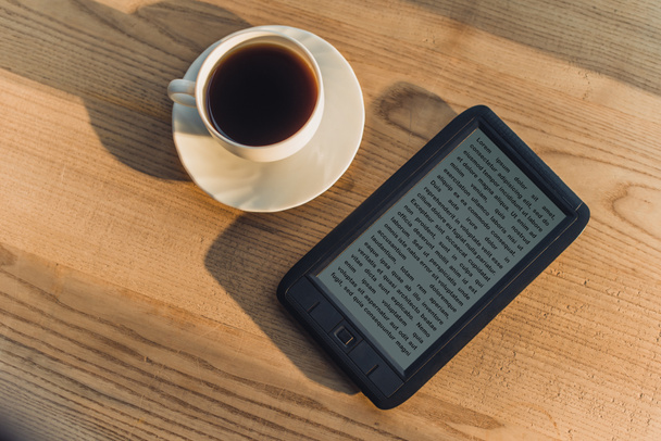 Черная электронная книга, лежащая возле чаши с напитком
  - Фото, изображение