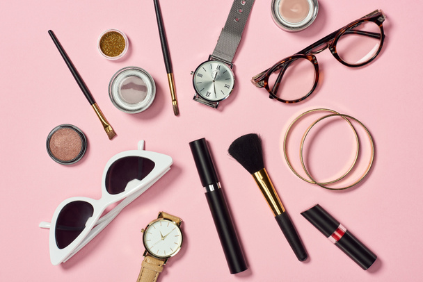 Top view of watches, lipstick, glasses, sunglasses, eyeshadow, blush, cosmetic brushes, bracelets and mascara  - Photo, Image
