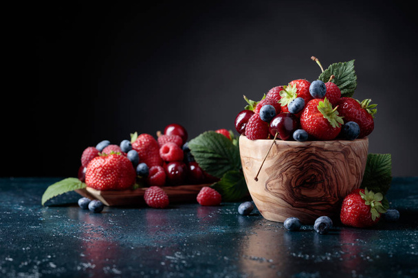 Beeren Nahaufnahme bunte Mischung aus Erdbeere, Blaubeere, Himbeere und Süßkirsche im Studio auf dunklem Hintergrund. - Foto, Bild