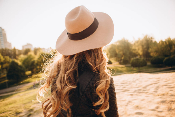stylish girl in a hat outside in the park at sunset - 写真・画像