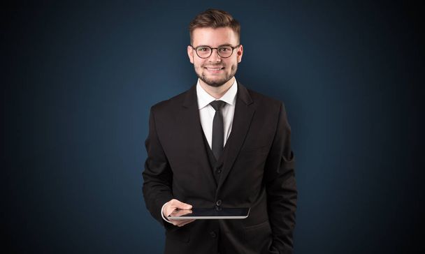 Businessman holding tablet with dark background - Zdjęcie, obraz